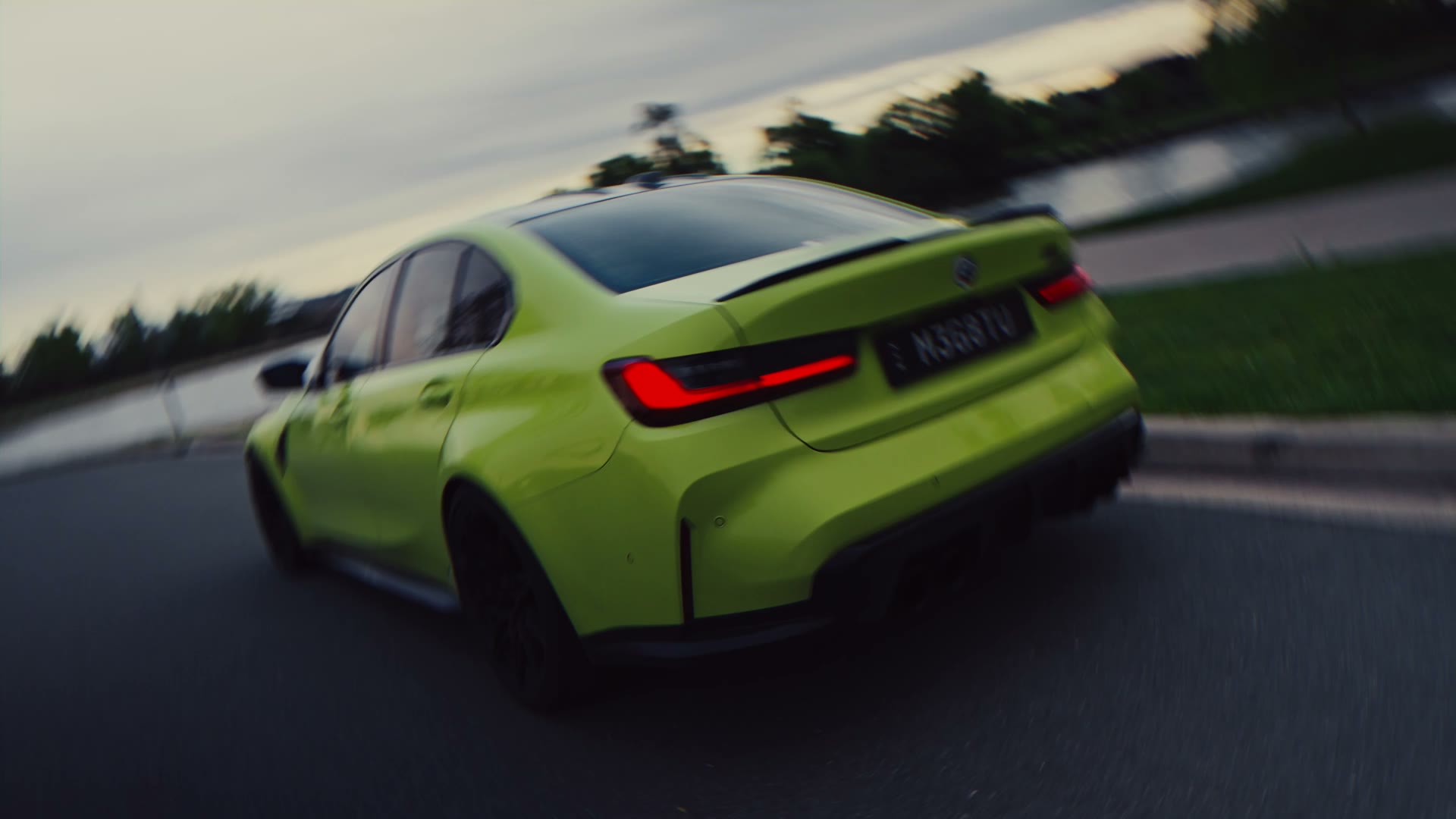 Lime green BMW M3 driving along the lake