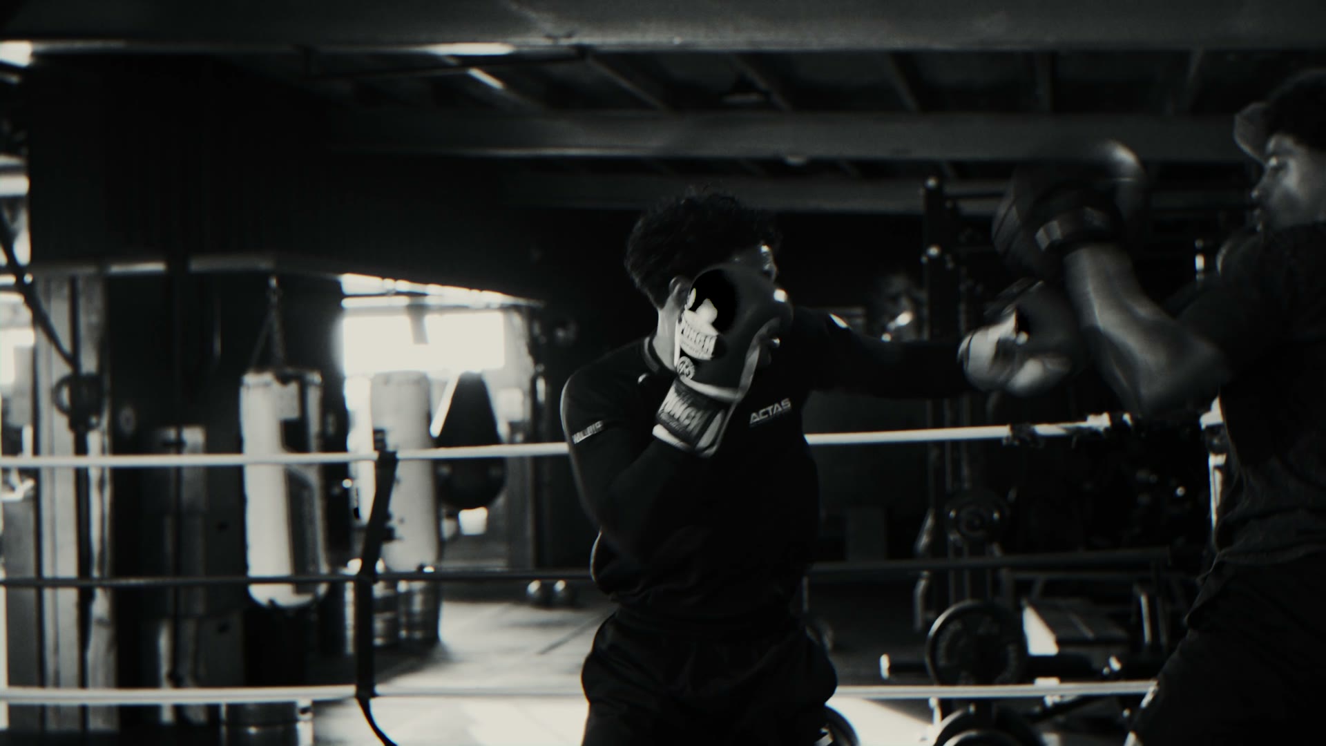 Black and white shot of a boxer working the pads in the ring