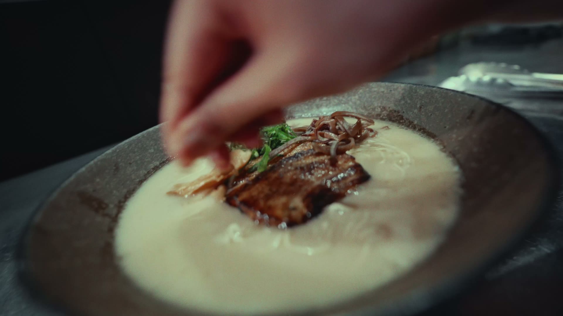 Spring onion going onto a bowl of tonkotsu in the Ikigai Ramen kitchen
