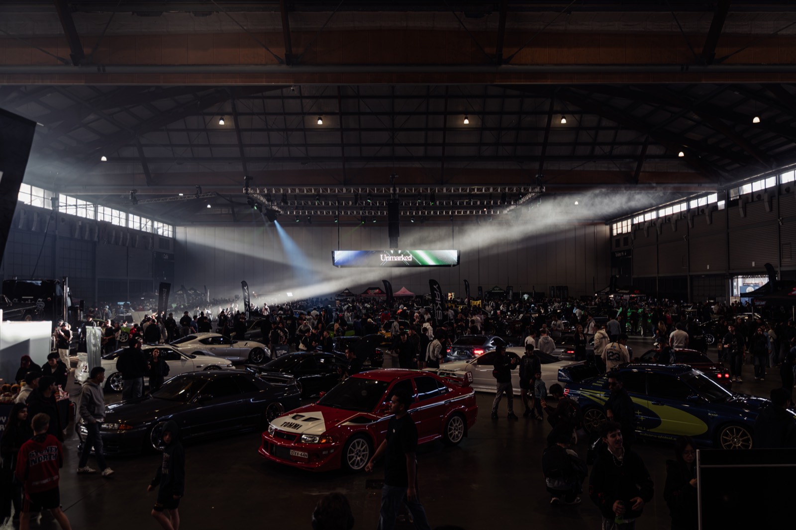 Light beams over the crowd and the cars in the Unmarked hall
