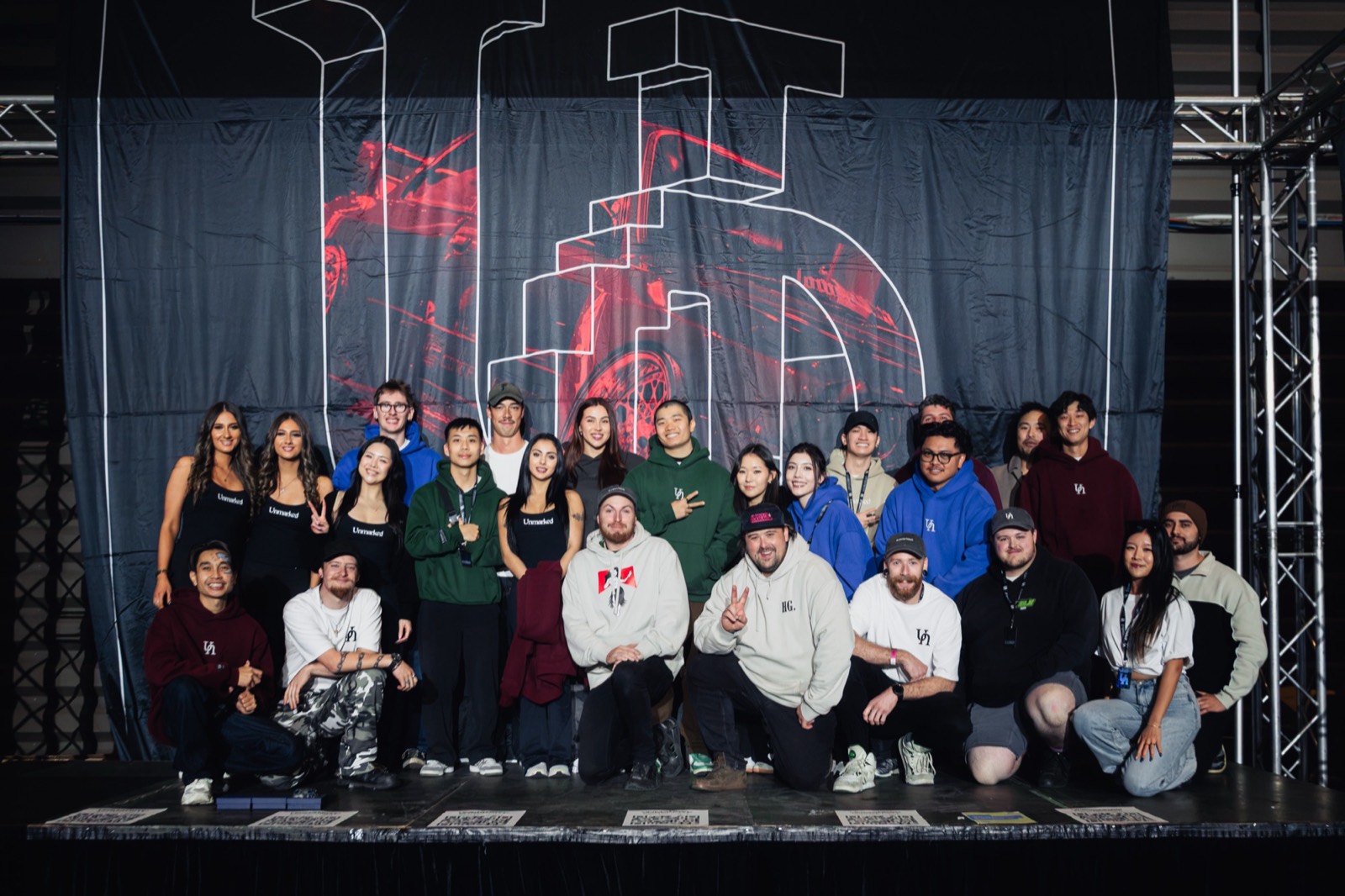 The Unmarked crew on stage in front of their banner