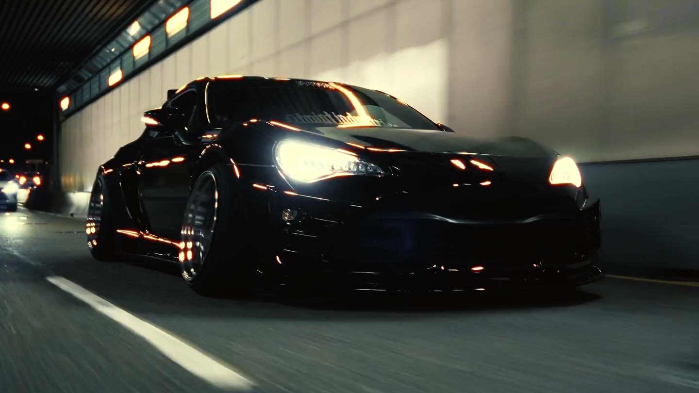 Lowered black coupe driving through a lit tunnel at night
